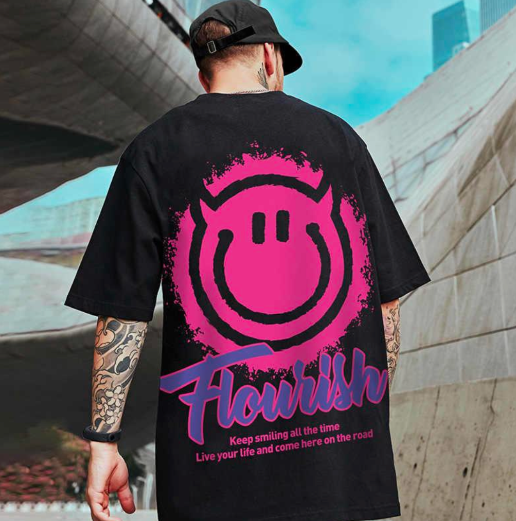 Person wearing a black t-shirt with a pink and purple logo and text, standing outdoors.
